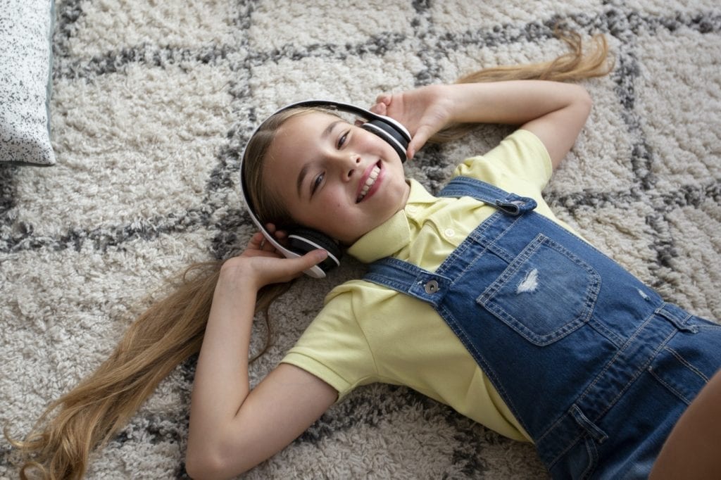 Teenager listening to music lying on carpet